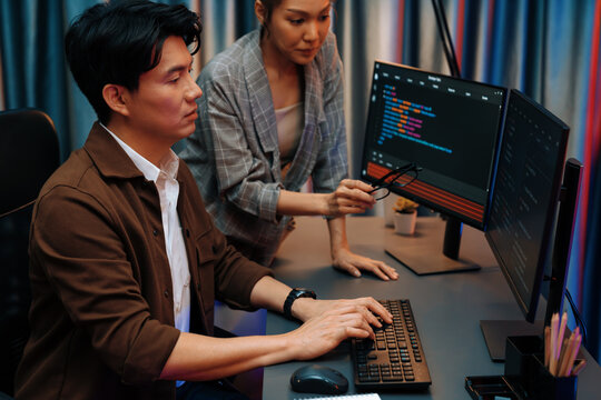 IT developers discussing with point to intelligent website development coder system running data online two screens information technology at neon light room at modern office. Infobahn.
