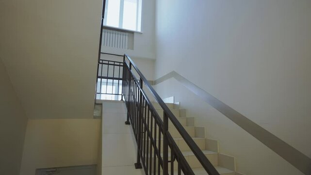 Staircase equipped with metal handrail in children hospital. Large windows create clear visibility without need for lighting during daytime