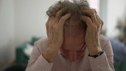 Senior man with head in hands, deeply distressed and frustrated, indoor setting, capturing...