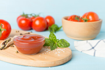 Delicious ketchup with spices and tomatoes on wooden table