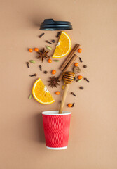 Red craft glass with a lid with ingredients for mulled wine, warm tea, sea buckthorn berries, honey, spices on a light background. Top view, layout. Warming autumn, winter drink.