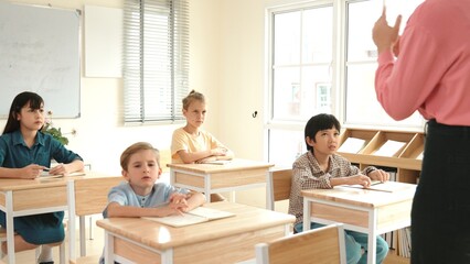 Back view of caucasian teacher teach diverse student while standing at blackboard. Professional instructor explain classwork while student looking and listen carefully. Education concept. Pedagogy.