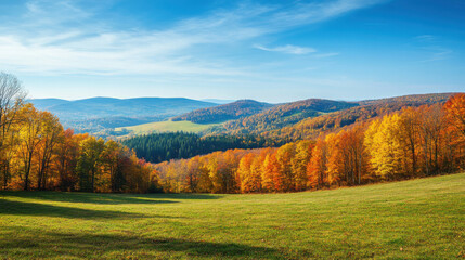 Fototapeta premium A scenic autumn landscape featuring rolling hills covered in vibrant fall foliage and a clear blue sky overhead.