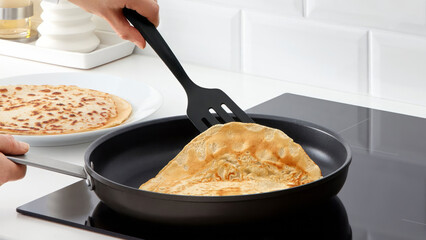 Closeup of a person flipping pancakes in a frying pan.