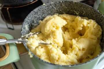 nostalgic kitchen scene featuring a pot of creamy mashed potatoes, accompanied by a perforated metal masher, evokes warmth and comfort celebration of homemade meals