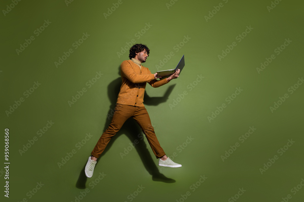 Sticker full length photo of handsome young guy hold netbook running hurry dressed stylish brown garment iso