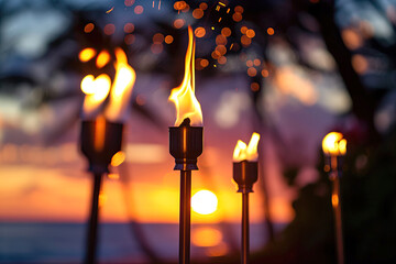 Tiki torches with flames glowing brightly at sunset, creating a warm, tropical atmosphere with vibrant colors and bokeh in the background.