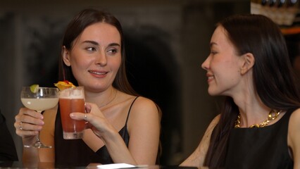 Beautiful woman taking Paloma cocktail drinks smoothy with cherry and lemon from bartender created drink special menu beside with friend holding Margarita glass with refreshing beverage. Vinosity.