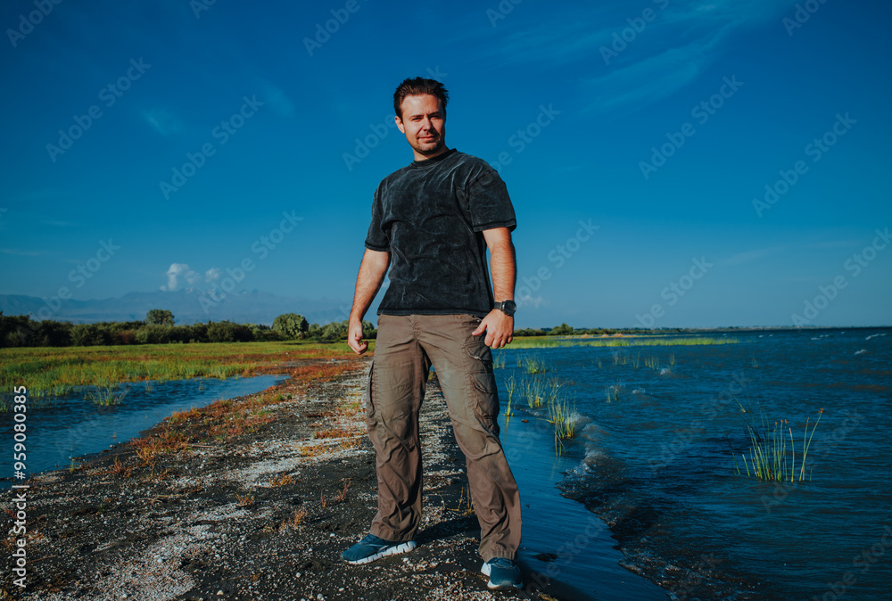 Canvas Prints Young handsome man standing on lake shore on summer day