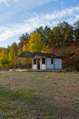 Old abandoned house in the autumn forest on a background of blue sky