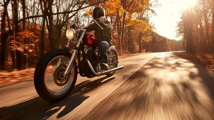 Obraz premium A lone biker on a motorcycle journeys through a breathtaking fall forest filled with vibrant autumn colors and beautiful scenery.