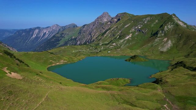 4K Aerial Drone video of the most beautiful mountain lake Schrecksee in Bavarian Alps with the cows feeding on lush green grass on a sunny day with blue skies and rocky hill tops surrounding
