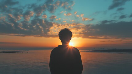 Silhouette of man watching sunset over calm ocean horizon, copy space