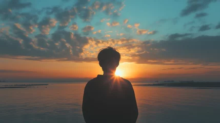 Fotobehang Silhouette of man watching sunset over calm ocean horizon, copy space © James