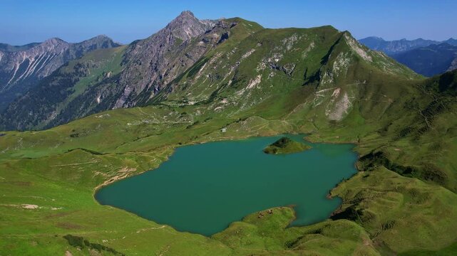 4K Aerial Drone video of the most beautiful mountain lake Schrecksee in Bavarian Alps with the cows feeding on lush green grass on a sunny day with blue skies and rocky hill tops surrounding