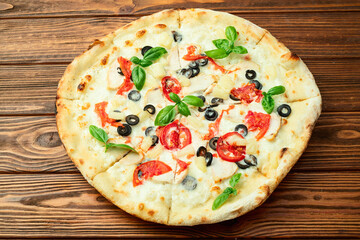 Pizza with mozzarella cheese , olives , chicken , pineapple , basil and tomatoes