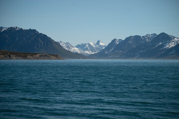 A bay surrounded by snow-capped mountains and dotted with ice formations. The magic of nature in its frozen splendor. A unique combination of ice and sea.Travel in cold weather, fresh air