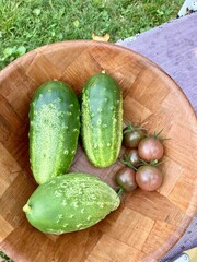 Organic cucumbers and tomatoes on a wooden bowl