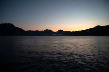 Stunning sunset over mountains and sea on wild natural islands in the northern region of the world, a journey to the cold and fiery sunsets of nature