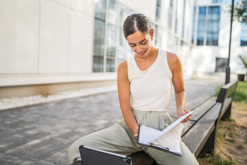 young business woman work on clipboard, tablet in front the building