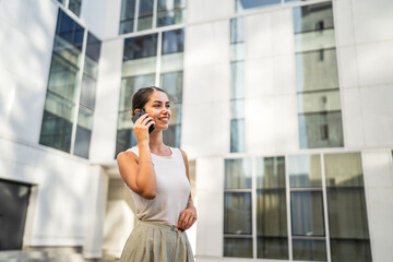 Fototapeta premium Portrait of young woman talk on mobile phone in front building