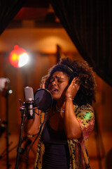 Portrait of a hispanic woman singer recording a new song in a music studio