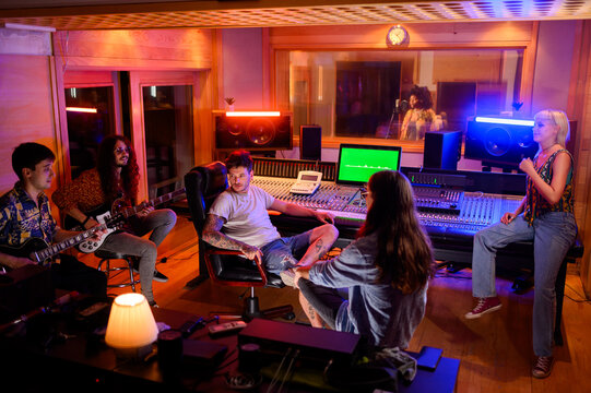 Portrait of a diverse band with their producer in a modern music studio