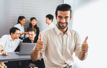 Confidence and happy smiling businessman portrait with background of his colleague and business team working in office. Office worker teamwork and positive workplace concept. Prudent