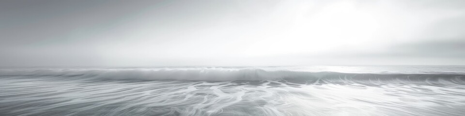 Obraz premium Minimalist monochromatic seascape featuring undulating waves and smooth water, taken during daylight with a long exposure.