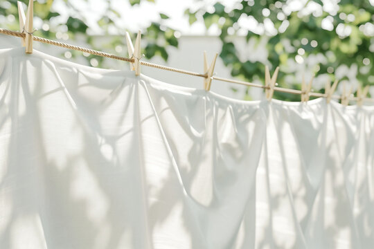 Clean white sheets drying on a line, laundry with clothes pins on a rope, clean clothesline dry laundry line, empty space for text, mockup of fresh laundry drying outdoors