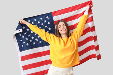 Young woman with USA flag on light background