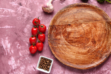 Wooden kitchen board, tomatoes and spices on color background