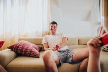 Young man enjoying playing card games with friends in a cozy living room