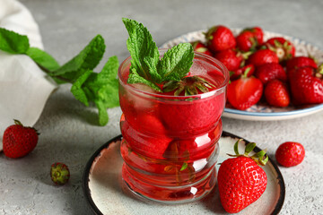 Glass of infused water with strawberry and mint on grey background