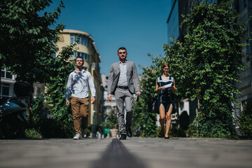 A confident group of professionals walking through an urban environment, representing teamwork and...