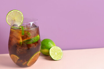 Glass of cold Cuba Libre cocktail on color background