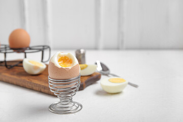 Holder with boiled chicken egg on white background