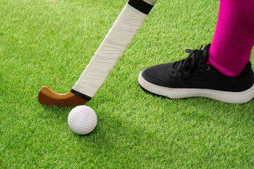 Field with ball and stick for hockey, fitness and training in the stadium. Close-up, ground and equipment for a competition, game or tournament in a stadium or grass in bokeh.