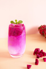 Close-up of a glass of dragon fruit cocktail with mint, pink background