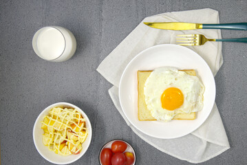 Bread on white plate, fried eggs, fruit salad, top view, terrazzo background