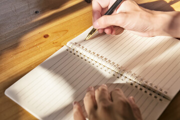 Close-up of hand writing on a notebook, light and shadow