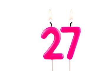 Pink number 27 birthday candle lit on white background