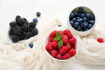 Bowls with different fresh berries on light background, closeup