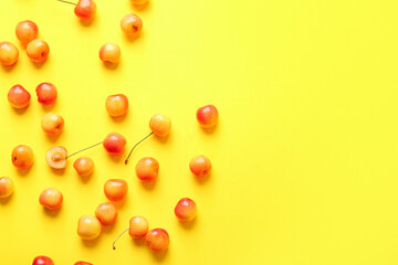 Many sweet yellow cherries on yellow background