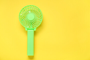 Small green electric fan on yellow background