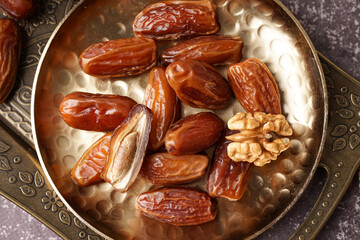 Plate with dried dates and nuts on grey background