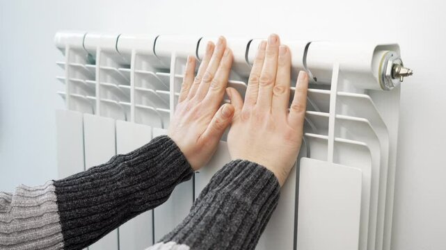 Close-up of woman hands heating touching central radiator thermostat save energy power cold temperature closeup. Domestic warming cost price increase control household expenses reduce money economy