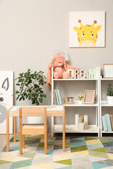 Interior of children room with toys, pictures, table and shelving units