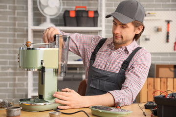 Male worker repairing coffee machine at table in workshop