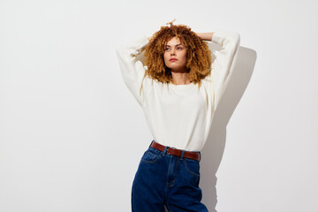 Stylish young woman with curly hair in casual attire against a minimalistic white background,...